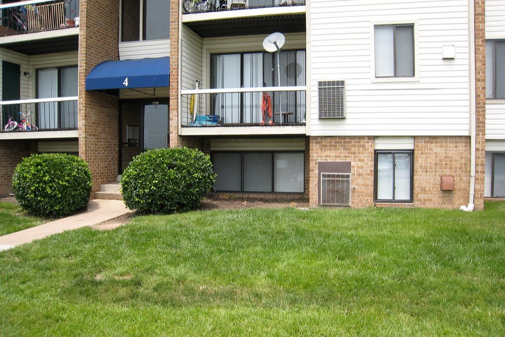 A low-rise apartment building with balconies and a front lawn