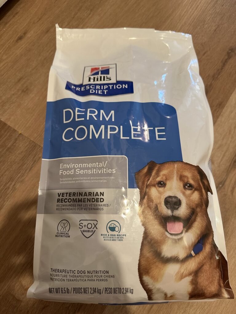A bag of Hill’s Prescription Diet Derm Complete dry dog food, Environmental/Food Sensitivities, 6.5 lb, on a wooden floor